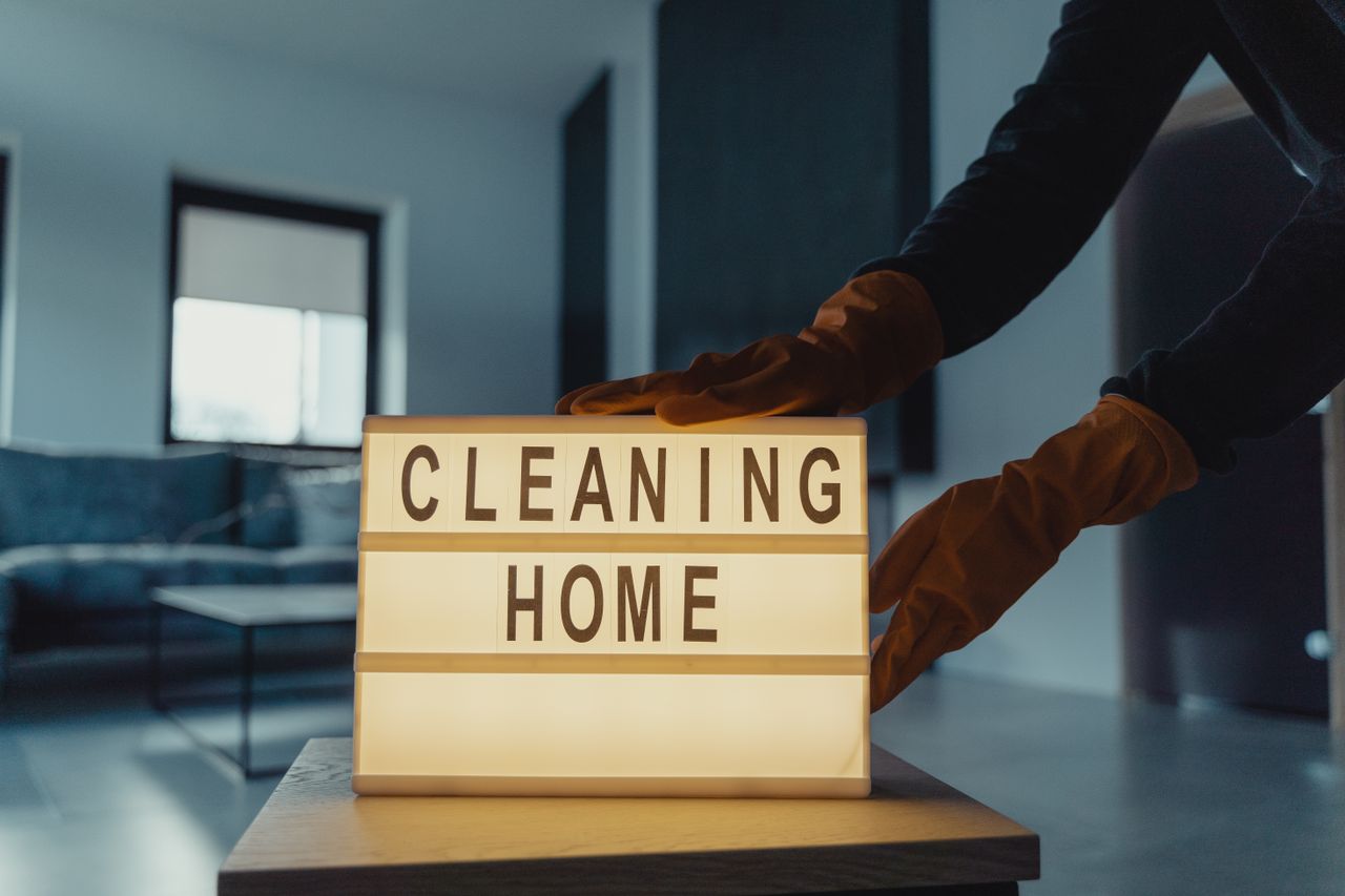 services-01 Close-up of hands with rubber gloves holding an illuminated lightbox saying Cleaning Home.